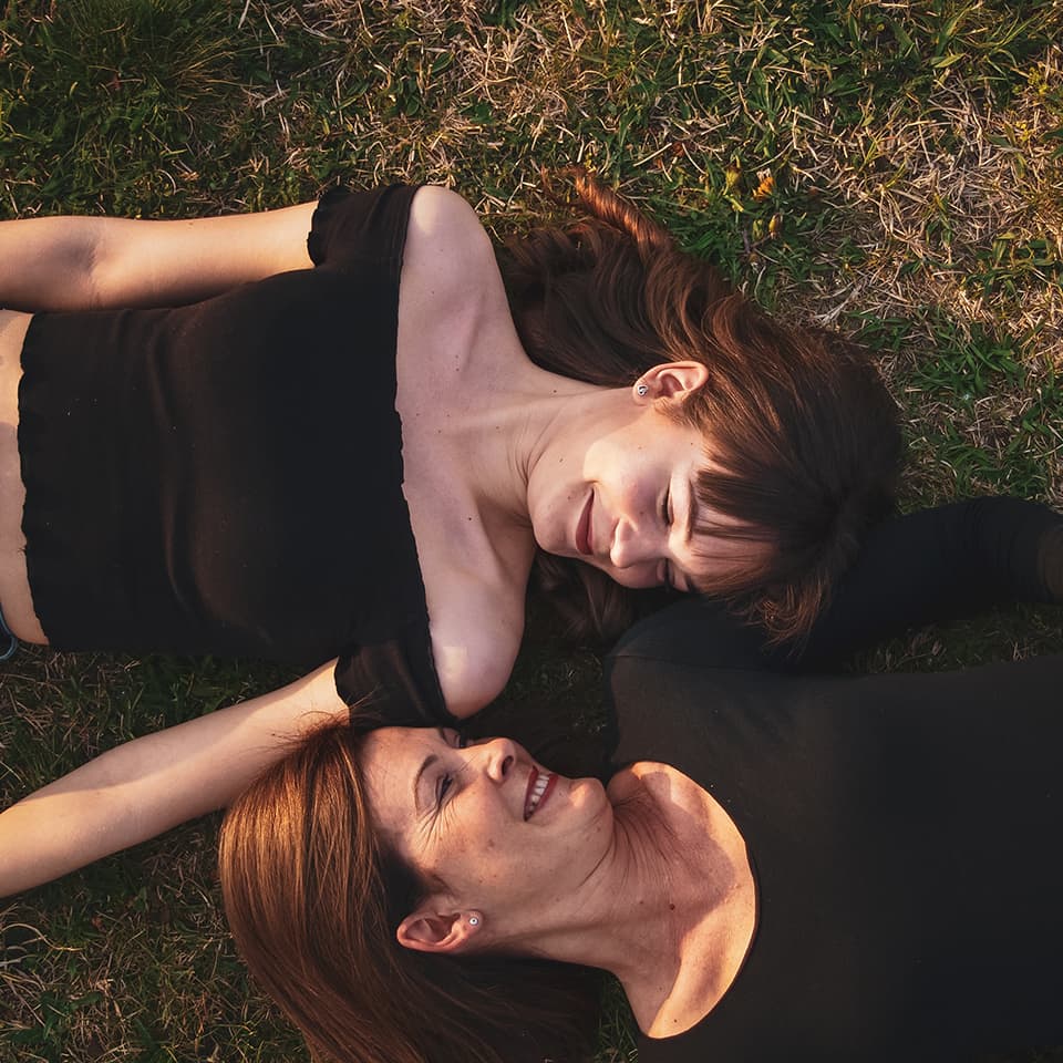 Mother and daughter lying in grass