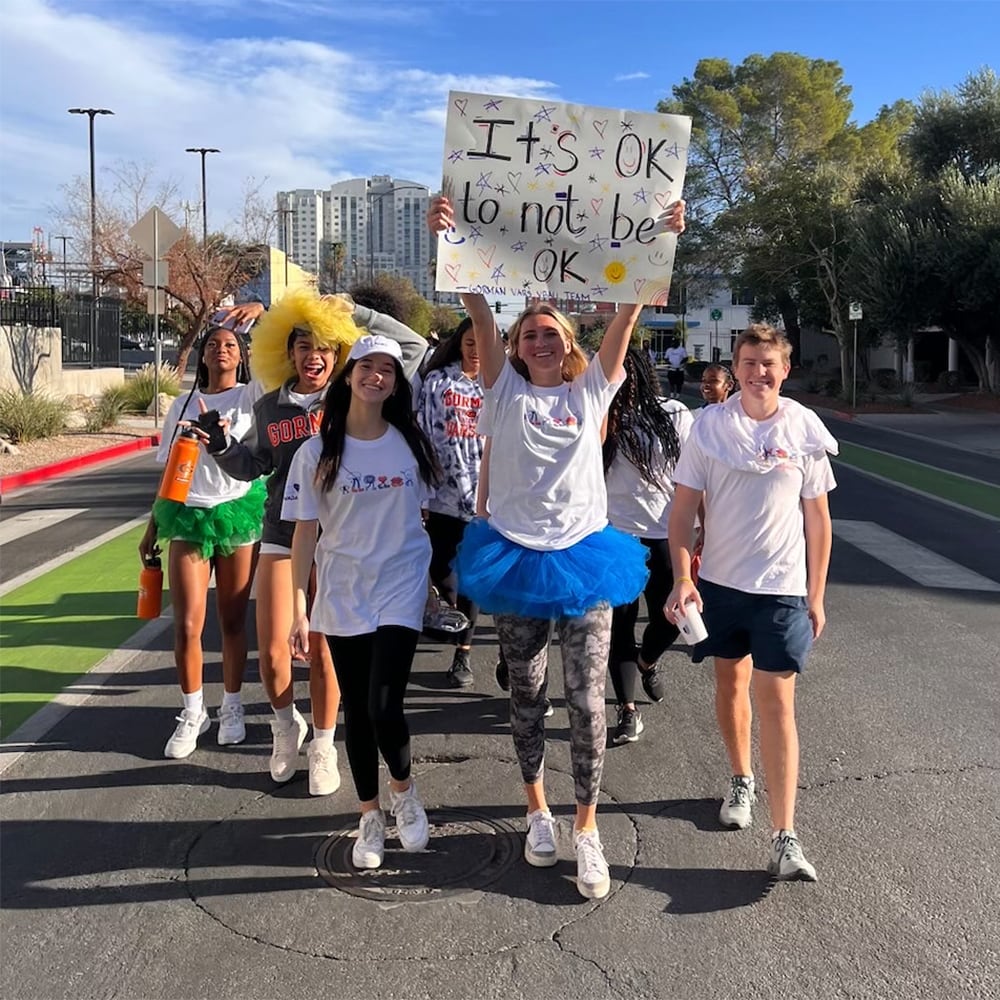 Group of youths walking with a sign that says "It's OK to not be OK"