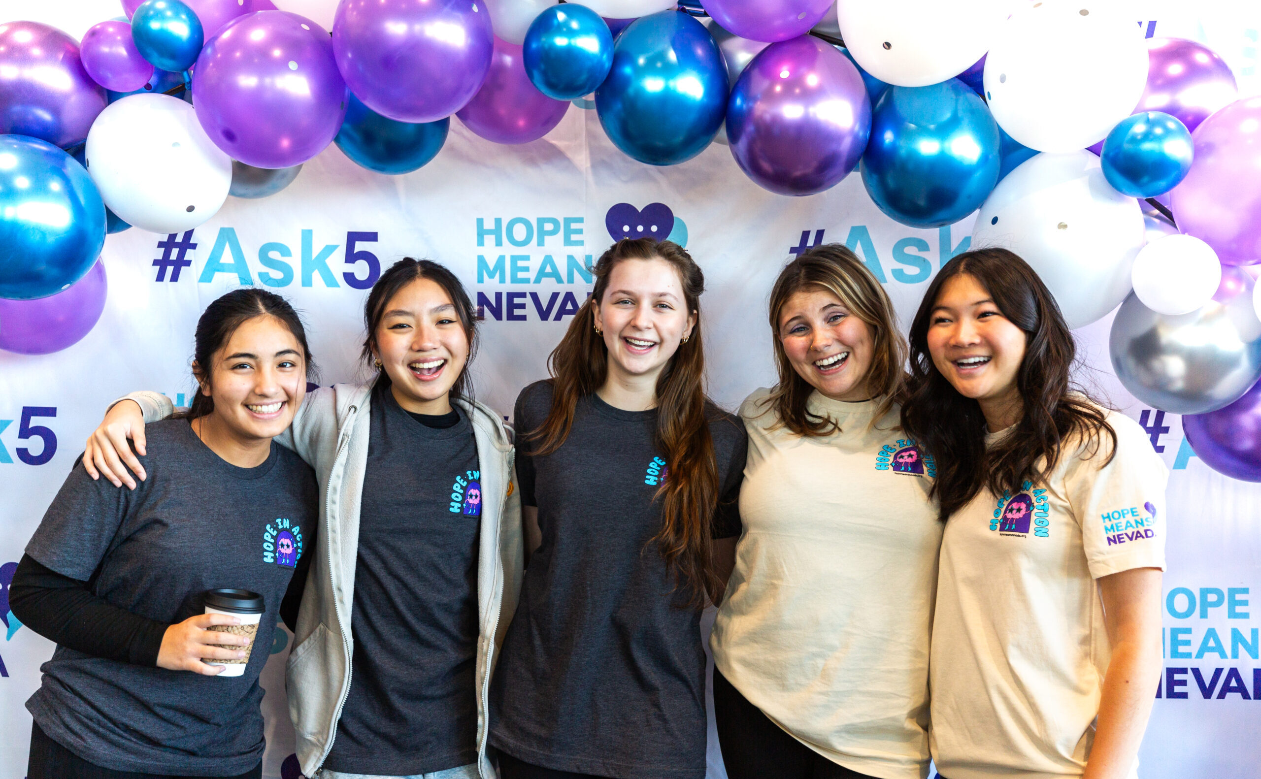 Five smiling people in matching Hope Means Nevada shirts stand under a balloon arch with the #Ask5 hashtag.